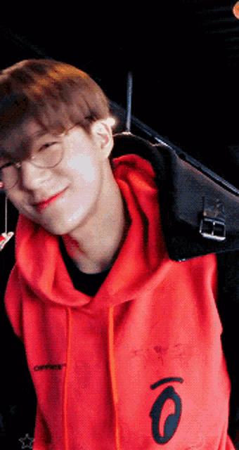 a young man wearing glasses and a red hoodie with the number 0 on it