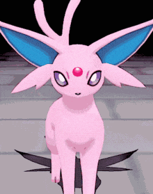 a pink cartoon character with blue ears and a red spot on its forehead