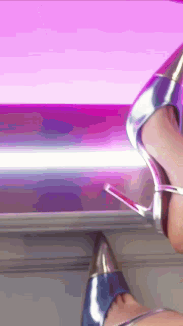 a woman wearing a pair of silver high heels is standing in front of a pink light