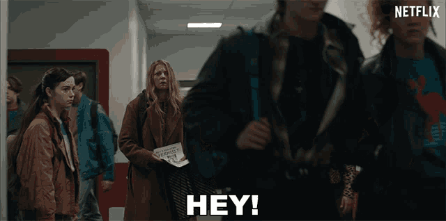 a group of people are walking down a hallway and the word hey is visible