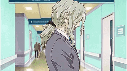 a man with long blonde hair is standing in a hallway .
