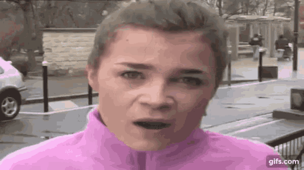 a woman in a pink jacket is making a funny face in front of a parking lot .