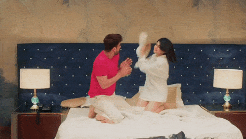 a man and a woman are having a pillow fight in bed