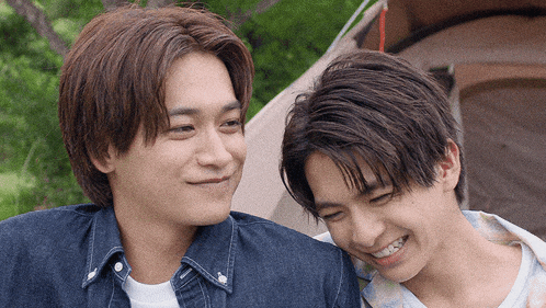 two young men are looking at each other and smiling