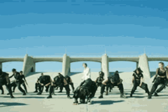 a group of people are dancing in front of a bridge in the desert