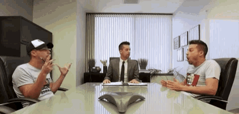 three men are sitting around a conference table talking