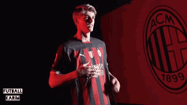 a man in a black and red shirt with the acm logo in the background