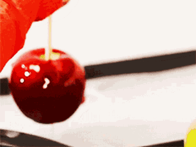 a red apple with a toothpick hanging from it