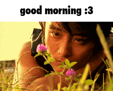 a man laying in the grass with purple flowers and the words good morning