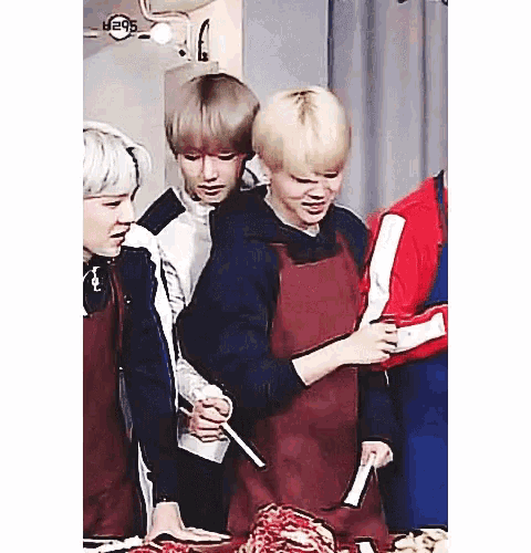 a group of young men are standing around a table holding knives .