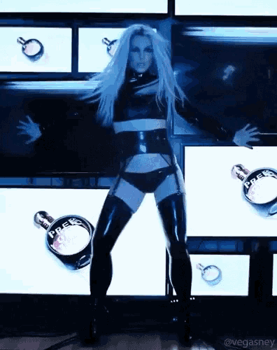 a woman in a black outfit is dancing in front of a display of perfume bottles