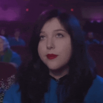 a woman in a blue shirt and red lipstick is making a funny face .