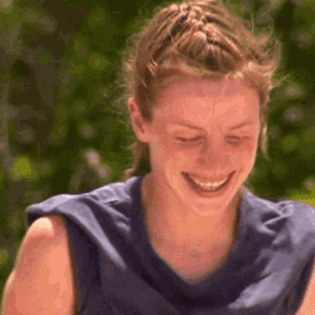 a woman in a blue shirt is smiling and laughing .