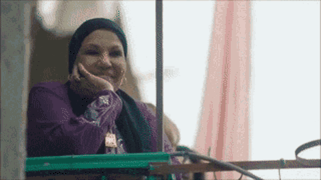 a woman is sitting on a balcony with her hand on her chin .