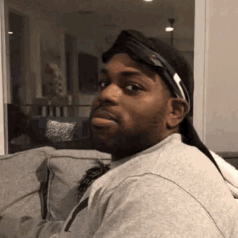 a man sitting on a couch wearing a hat