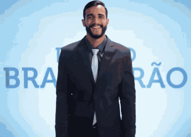 a man in a suit and tie is smiling in front of a sign that says bra