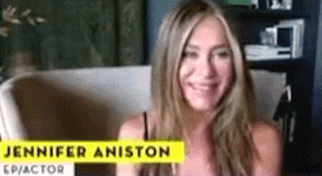 a woman is smiling and sitting in a chair with a yellow sign that says jennifer aniston ep / actor .