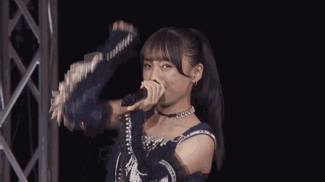 a girl singing into a microphone with a ponytail