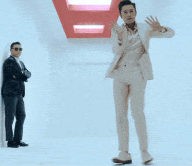 a man in a suit and sunglasses stands in front of another man