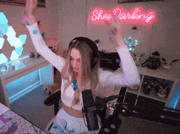 a woman wearing headphones stands in front of a neon sign that says shes darling