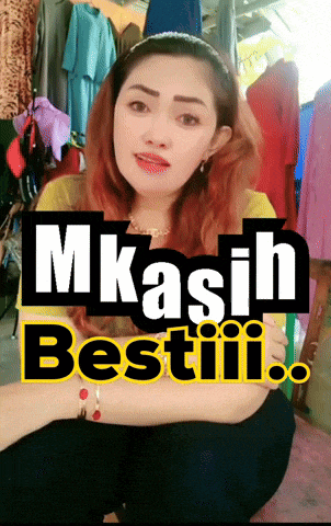 a woman is sitting in front of a sign that says mkasih bestiii