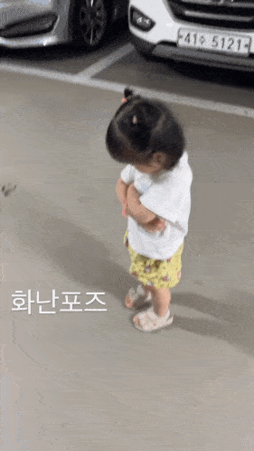 a little girl is standing in a parking lot in front of a car with a license plate that says f41 5121