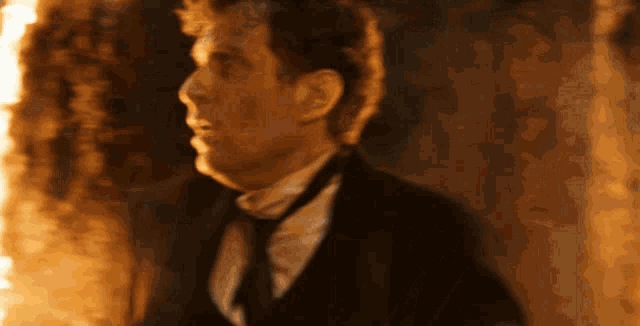 a man in a suit and tie stands in front of a fireplace