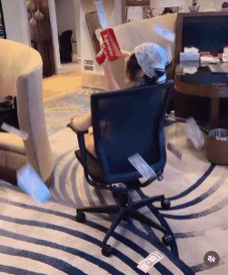 a person wearing a supreme hat is sitting in a chair in a living room