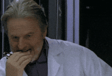 a man with a beard wearing a lab coat is eating something