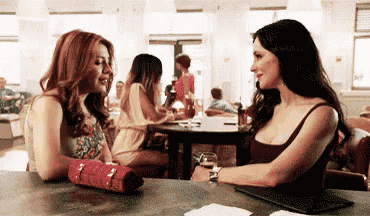 two women are sitting at a table talking to each other in a restaurant