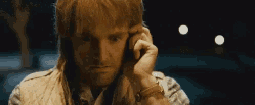 a man is talking on a cell phone while wearing a vest .