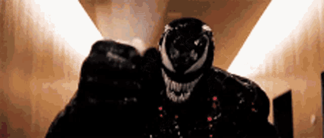 a close up of venom 's face in a dark hallway .