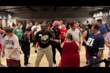 a group of people are dancing in a room including a man wearing a shirt that says " yellow canton "