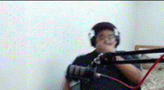 a man wearing headphones is holding a microphone in front of a white wall .