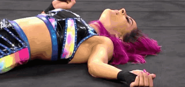 a woman with purple hair is laying on the floor .