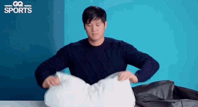 a man is holding a white pillow in his hands .