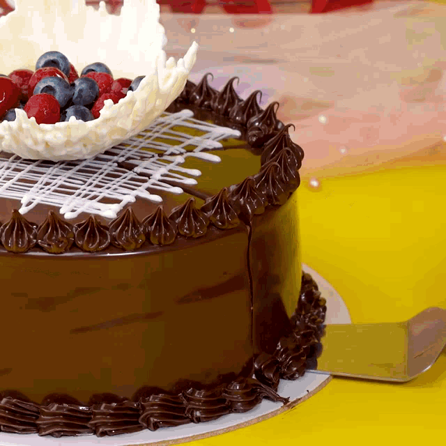 a chocolate cake with berries on top is sitting on a yellow table