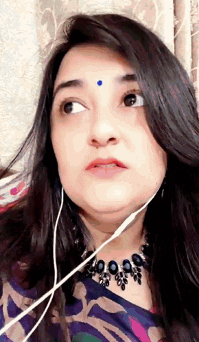 a woman with a blue dot on her forehead wearing headphones