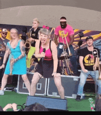 a woman singing into a microphone on a stage with a band behind her