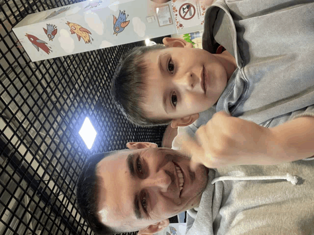 a man and a child are sitting in front of a box with birds on it