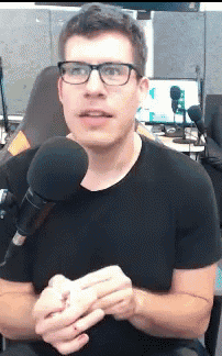 a man wearing glasses is talking into a microphone