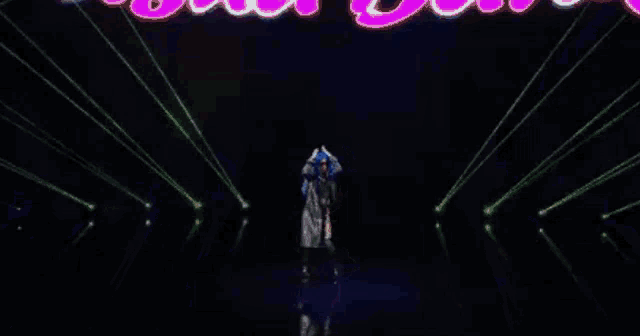 a woman with blue hair is dancing in a dark room surrounded by blue lights .