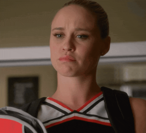 a cheerleader wearing a red white and black uniform is holding a racket