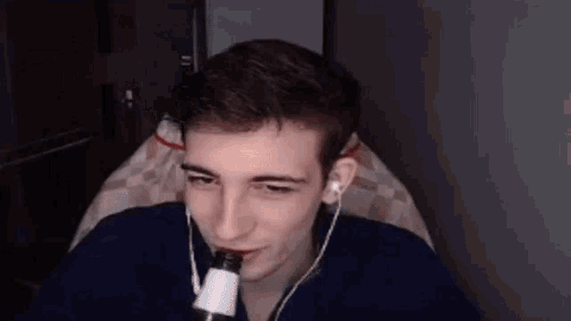 a young man is smoking a cigarette while wearing headphones and holding a bottle .