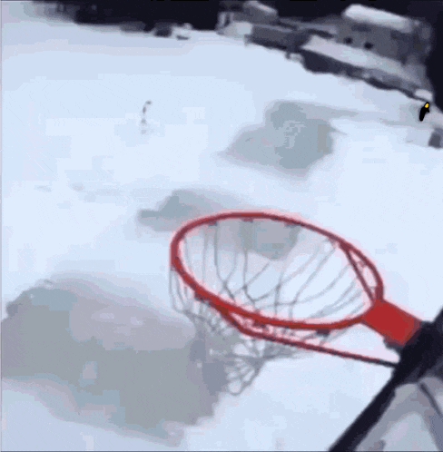 a basketball hoop in the snow with a person holding a picture in the air