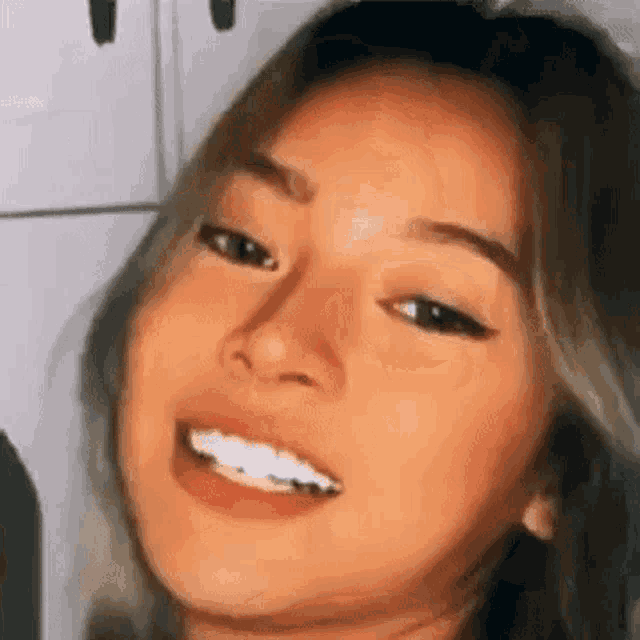 a close up of a woman 's face with white teeth smiling .