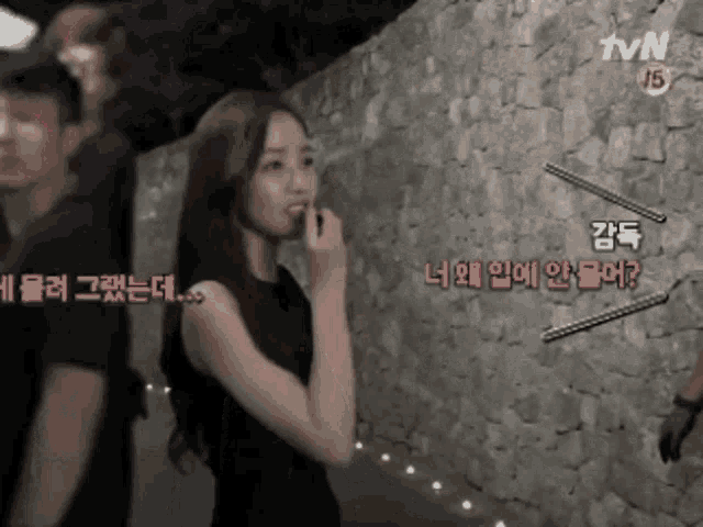 a woman is standing in front of a stone wall with tvn written on the bottom