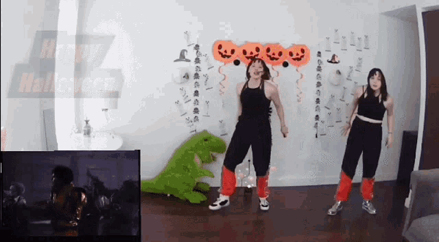 two women are dancing in front of a sign that says " happy halloween "