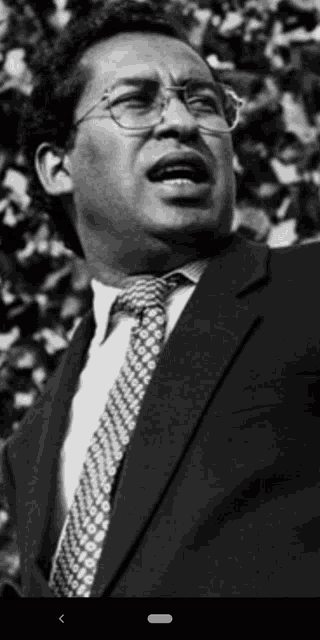 a black and white photo of a man wearing a suit and tie