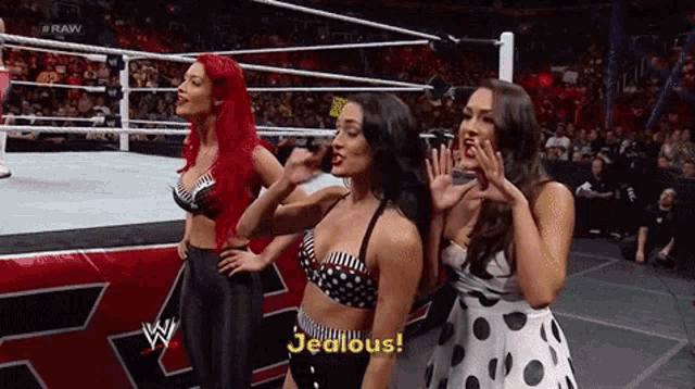 three female wrestlers are standing in a wrestling ring and one of them is saying jealous